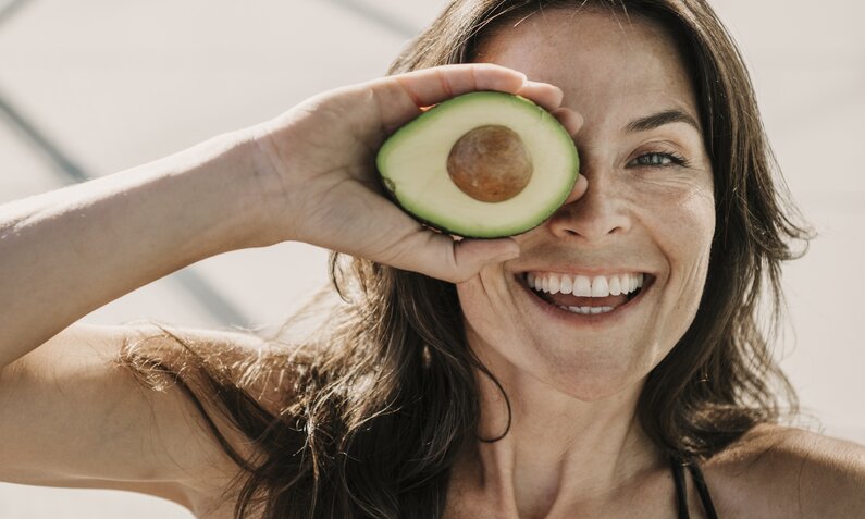 Frau hält Avocado und lacht | ©  Getty Images / Westend61