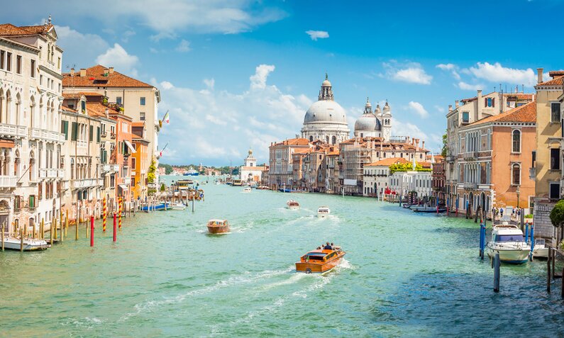 Bilck auf den Canale Grande in Venedig von der Akademiebrücke - mit vielen verscheidenen Booten auf dem türkisfarbenen Wasser und blauem Himmel über den prächtigen Häusern. | © Getty Images/Kirill Rudenko