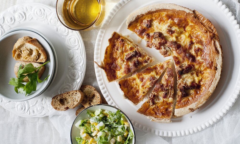 Quiche angerichtet auf Teller, daneben Salat. | © Getty Images / Magdalena Niemczyk - ElanArt