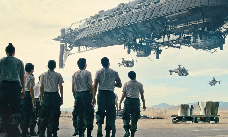 Eine Gruppe von Menschen starrt in einer Wüstenlandschaft in den Himmel in dem eine Art Raumschiff und Hubschrauber zu sehen sind in einer Szene aus der Prime Video Serie "Fallout" | © Amazon Content Services LLC
