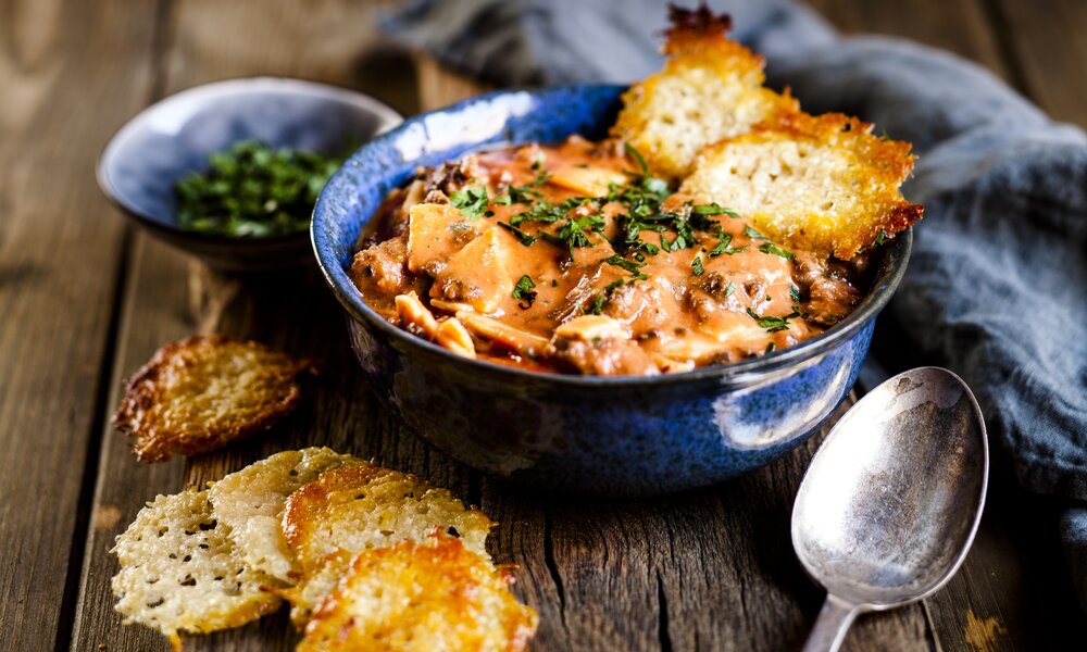 Deftige Suppe mit Parmesan-Cracker in Suppenschüssel. | © Getty Images / Westend61