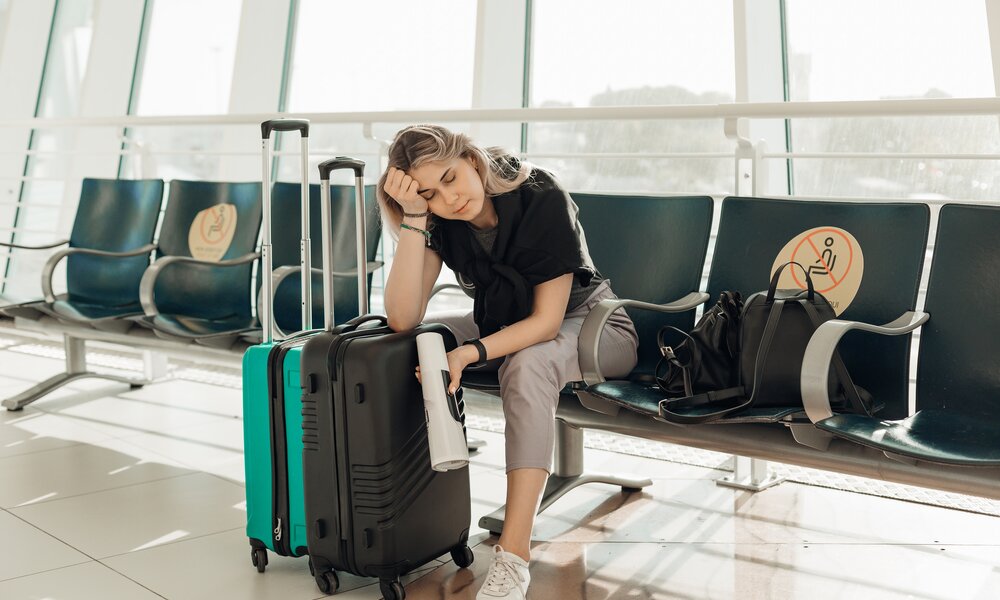  Frau sitzt erschöpft und enttäuscht am Flughafen | ©  Getty Images / Tatsiana Volkava