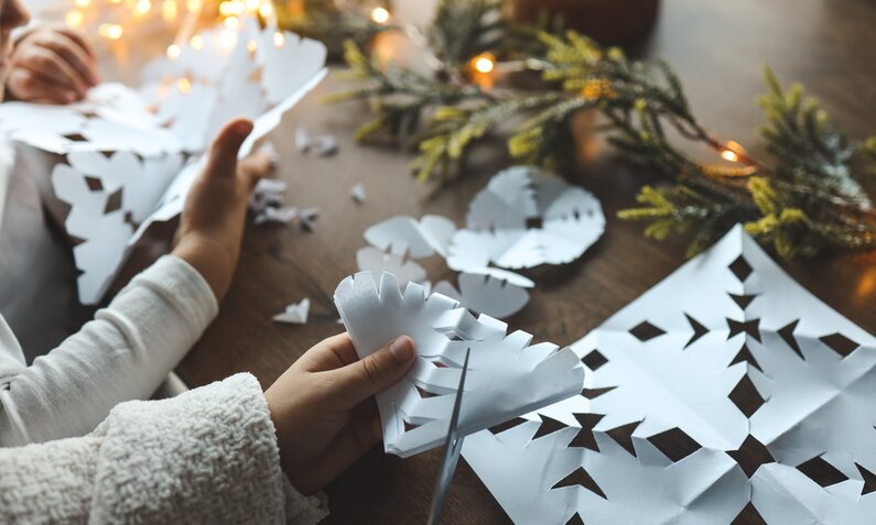 Hände basteln Papiersterne zu Weihnachten. | © Getty Images / Bohdan Bevz