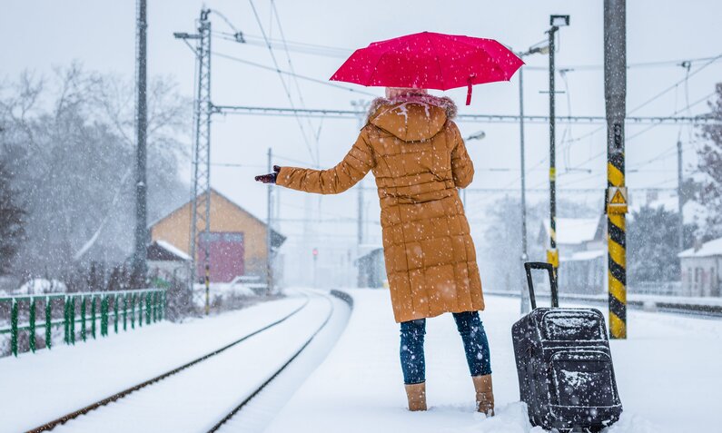 Frau wartet am verschneiten Gleis aus ihren Zug | ©  Shutterstock / encierro
