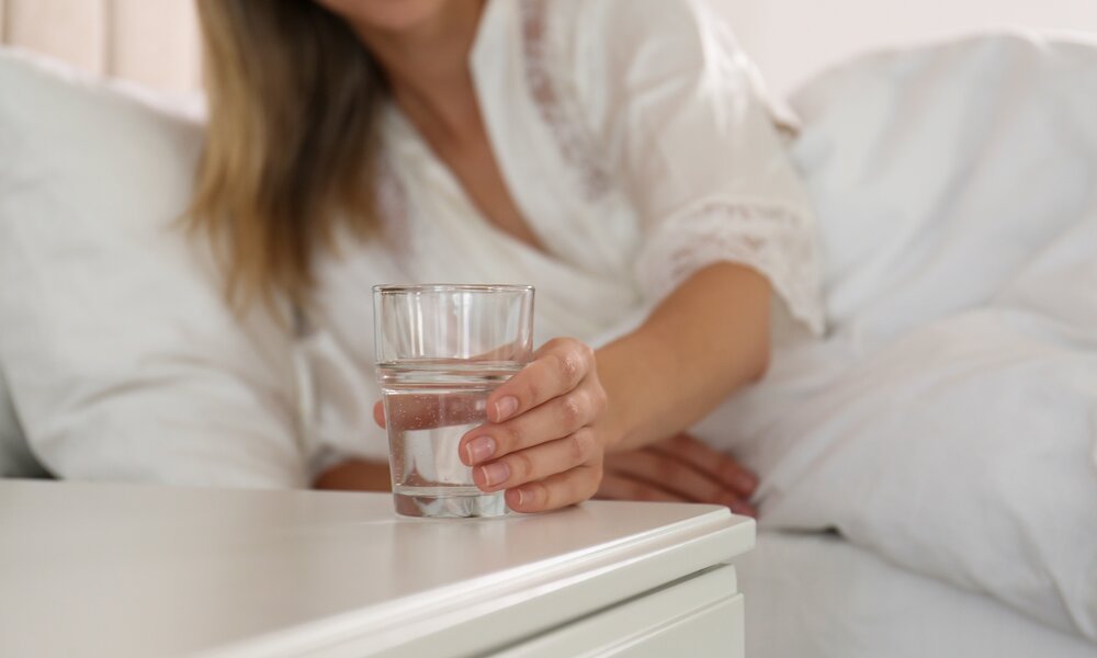 Frau greift nach Wasserglas | ©  Getty Images / Liudmila Chernetska