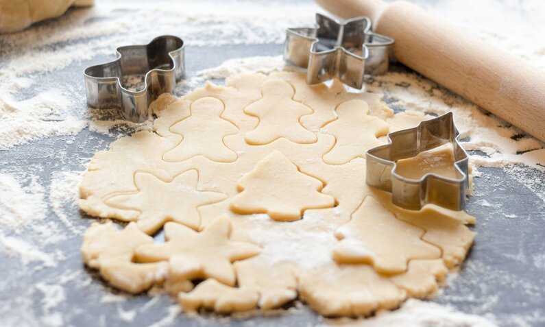 Hände stechen Kekse aus ausgerollten Mürbeteig. | © Getty Images / Nikolaeva Elena