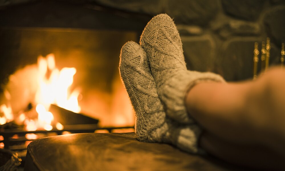 Füße in Stricksocken vor dem Kamin | ©  Getty Images / Johner Images
