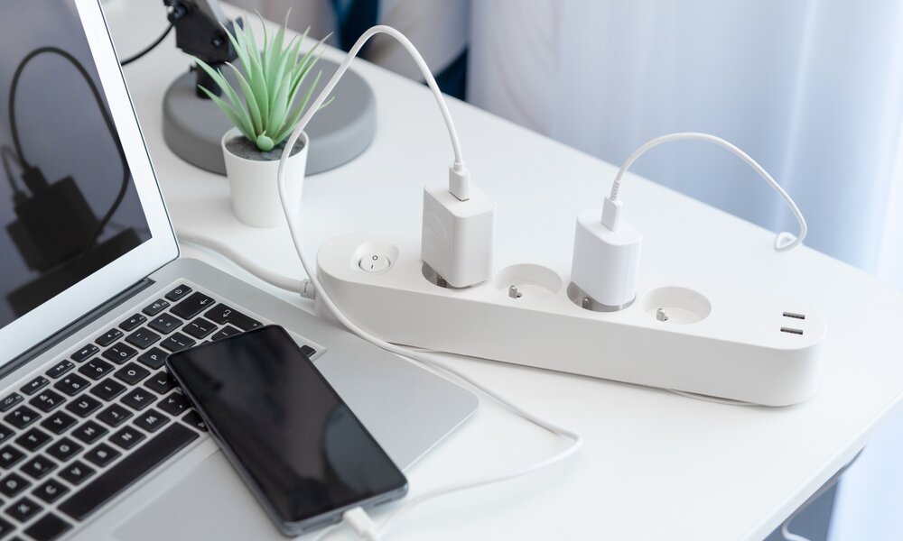 Schreibtisch mit Steckdosenleiste, Laptop und Handy | ©  Getty Images / simpson33