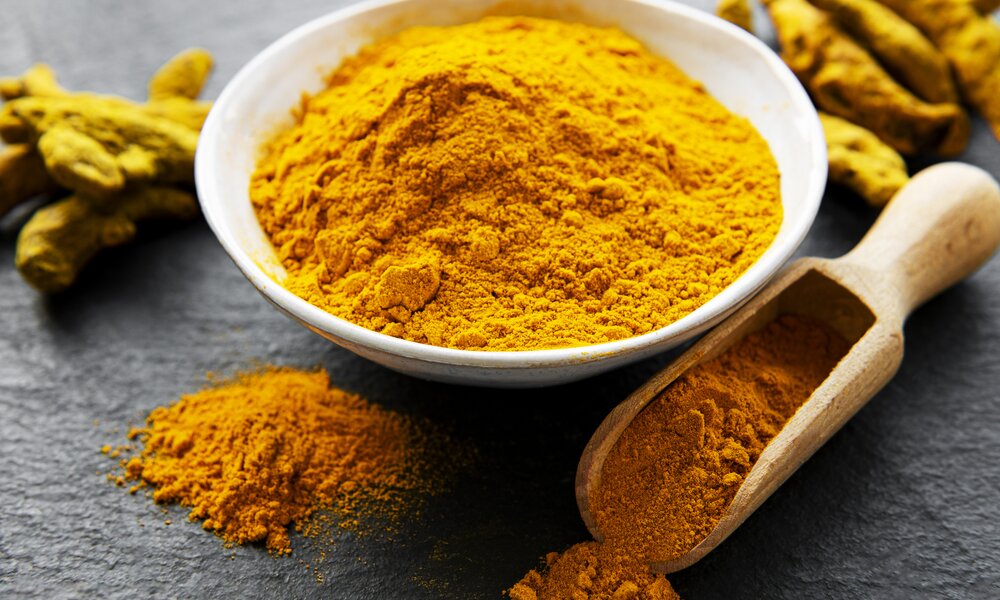 Currypulver in Schale, neben weiterem gelben verstreutem Pulver auf Untergrund. | © Getty Images / Nichifor Grigore / 500px