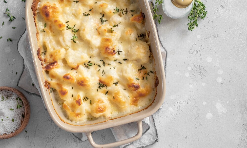 Blumenkohl-Gratin in weißer Auflaufform, bestreut mit Rosmarin. | © Getty Images / Azurita