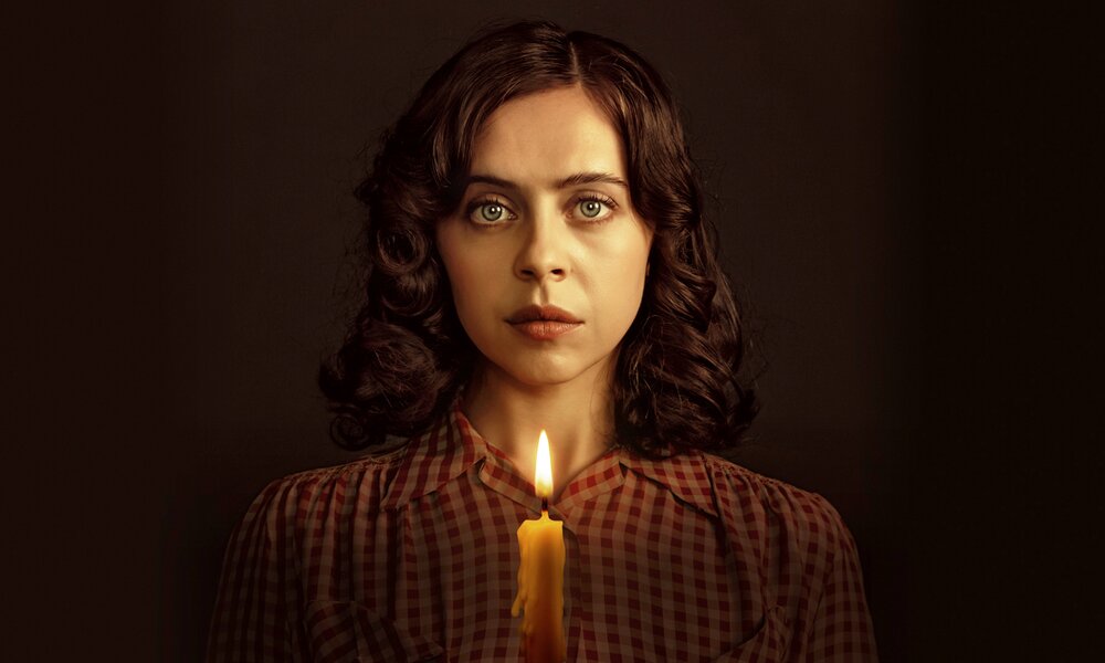 Nahaufnahme von Bel Powley als Miep Gies in der Serie "Ein Funken Hoffnung - Anne Franks Helferin". Sie steht im Dunkeln und hält eine brennende Kerze. | © Disney+