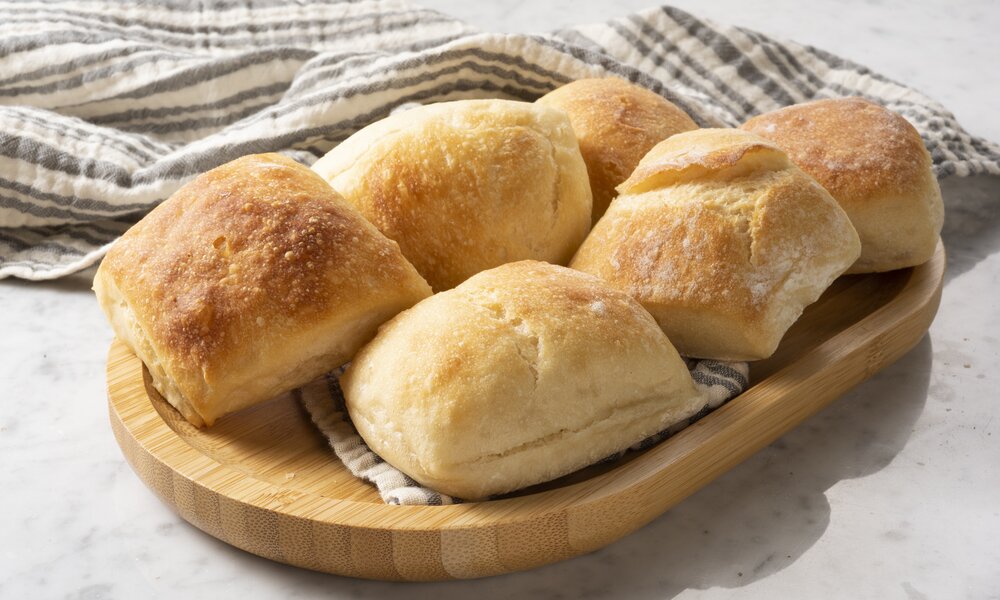 Brötchen auf einem Holzbrett, welches auf einem Geschirrtuch liegt. | © Getty Images / BURCU ATALAY TANKUT