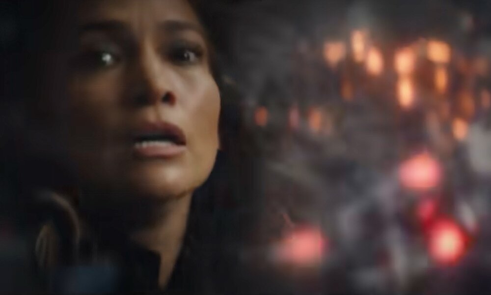 Nahaufnahme des erschrockenen Gesichts von Jennifer Lopez in einem Screenshot aus dem Trailer zum Netflix-Film "Atlas". Rechts von ihr ist eine Explosion zu sehen. | © Screenshot Trailer YouTube @Netflix