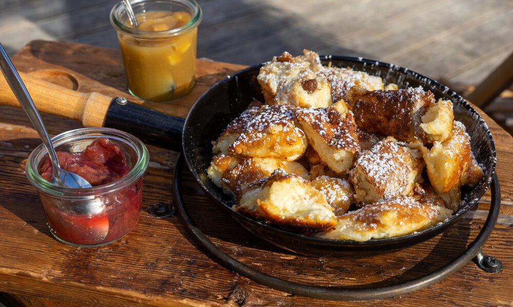 Kaiserschmarrn in gusseiserner Pfanne, daneben zweierlei Marmelade in Gläsern angerichtet. | © Getty Images / AndreaRR