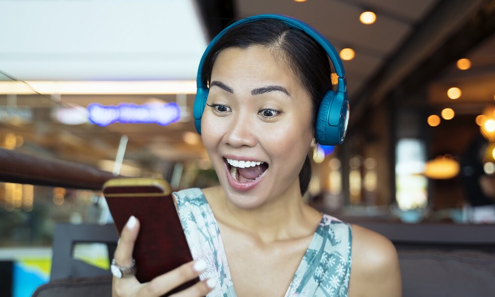 Junge Frau hört Podcast am Handy | © Getty Images / Enes Evren