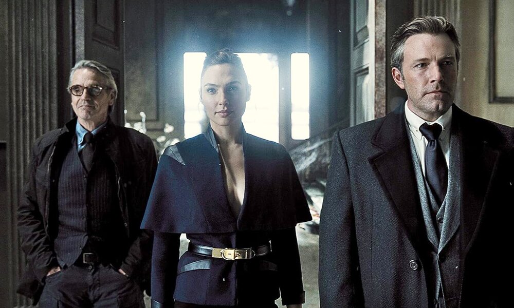 Ben Affleck, Gal Gadot und ein Co-Star gehen in dunkler Kleidung in einer Szene aus dem Kinofilm "Zach Snyder's Justice League" enen Gang entlang | © Bild von Amazon.de/Blu-ray Ausgabe von "Zach Snyder's Justice League"