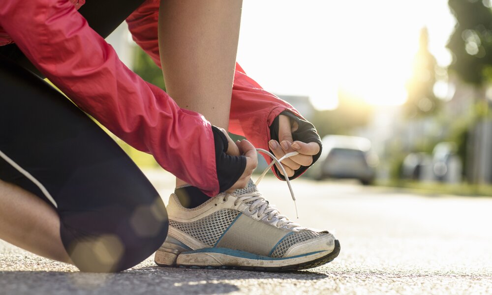Joggerin bindet sich die Schuhe | ©  Getty Images / Buero Monaco