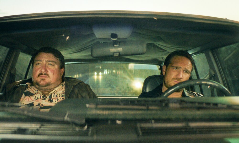 Christoph Krutzler und Frederik Lau fahren in einem Auto und blicken mit ernsten Gesichtern durch die Windschutzscheibe in einer Szene aus der Netflix-Serie "Crooks" | © Netflix