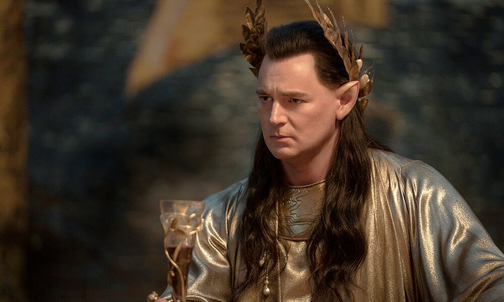 Benjamin Walker als Elbenkönig Gil-galad in prächtigem Gewand mit goldener Blätterkrone vor dunklem Huntergrund | © Prime Video/Amazon Studios