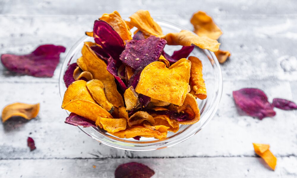 Rote und Lila Chips, selbstgemacht in einer weißen Schüssel. | © Getty Images / 	lacaosa