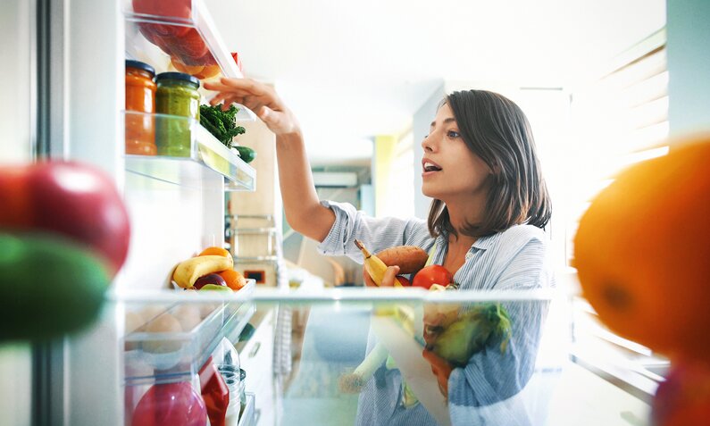 Frau räumt Lebensmittel in den Kühlschrank | ©  Getty Images/ gilaxia