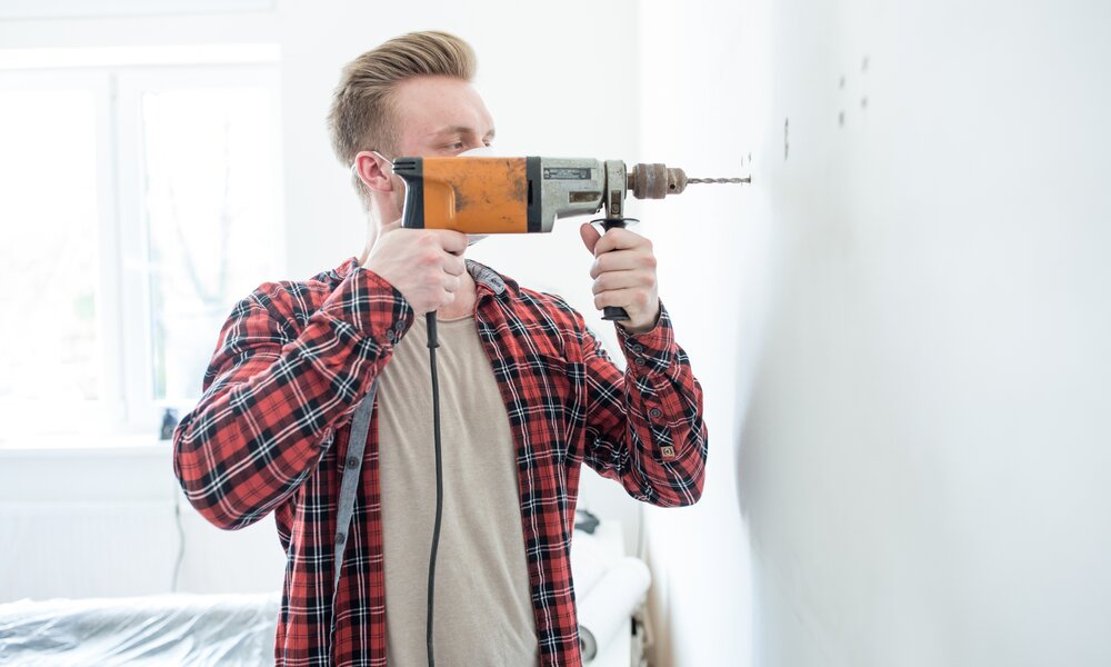 Mann bohrt in seiner Wohnung | ©  Getty Images/ Coolpicture