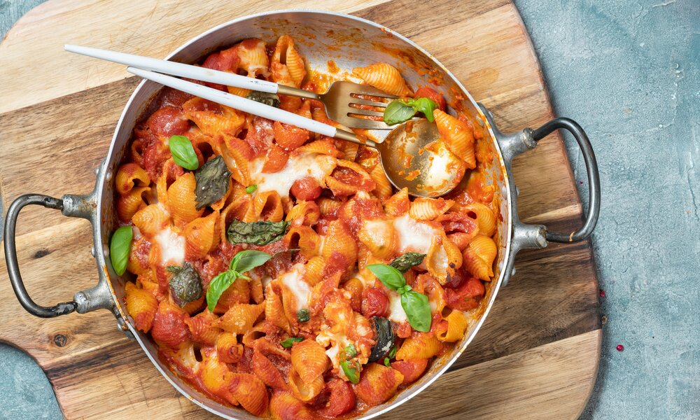 Cremige Pasta in Sahnesoße, darauf Cherry-Tomaten und kleine Mozzarella-Kugeln, garniert mit frischen Basilikum. | © Getty Images / Carlo A