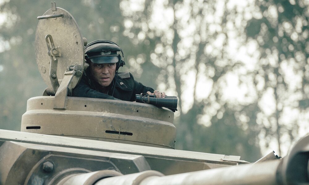 Wehrmachtssoldat blickt aus der Dachöffnung eines deutschen Panzers im Wald in einer Szene aus dem Prime Video Film "Der Tiger" | © Prime Video/Stanislav Honzík