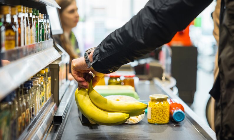 Mann legt Bananen auf das Kassenband | ©  Getty Images/ TommL