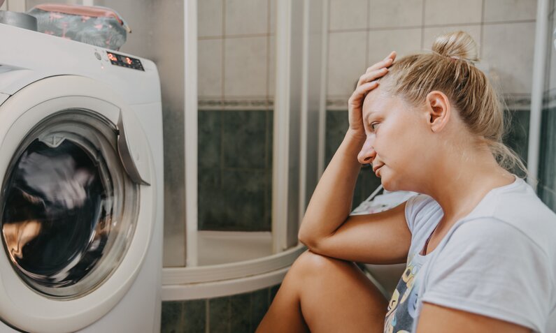 Frau schlägt sich vor Waschmaschine vor den Kopf | ©  Getty Images/ SimonSkafar