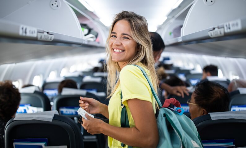 Glückliche junge Frau im Flugzeug | ©  Getty Images/ skynesher