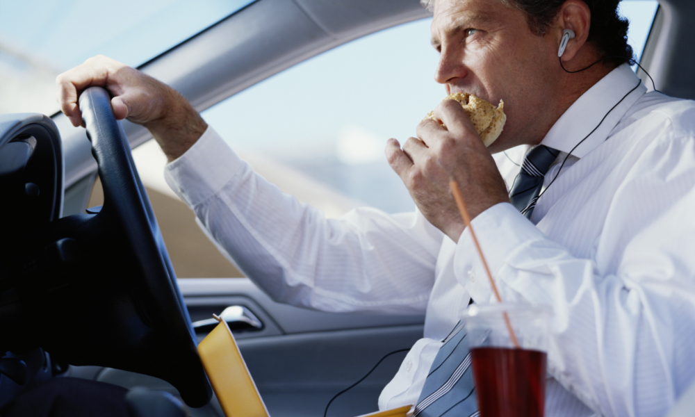 Mann isst am Steuer einen Burger | ©  Getty Images/ Tom Merton