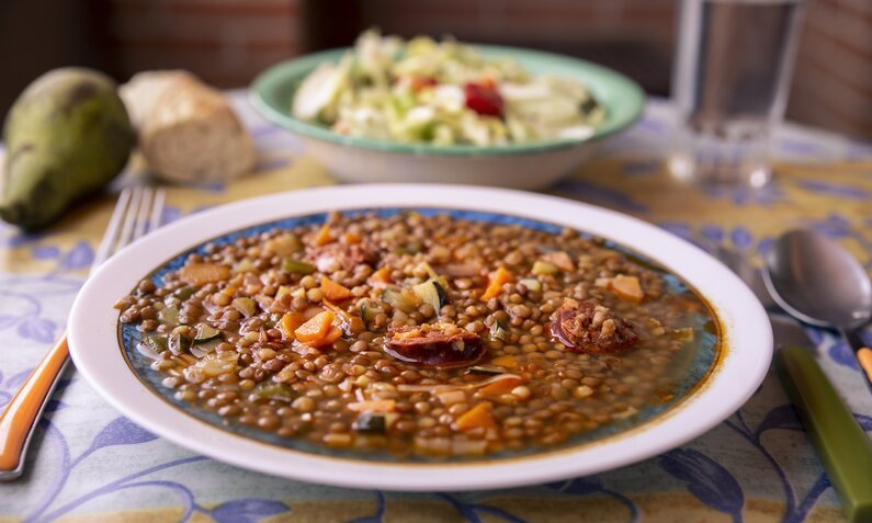 Traditionelle Linsensuppe in Suppenteller auf Esstisch. | © Getty Images / kemirada