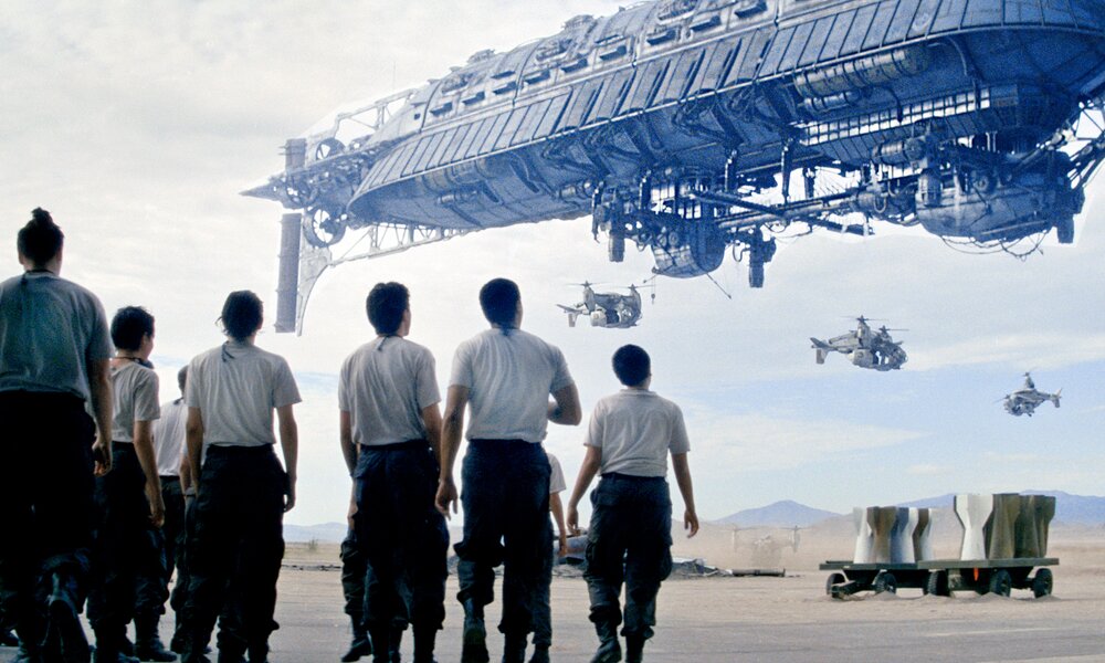 Eine Gruppe von Menschen starrt in einer Wüstenlandschaft in den Himmel in dem eine Art Raumschiff und Hubschrauber zu sehen sind in einer Szene aus der Prime Video Serie "Fallout" | © Amazon Content Services LLC