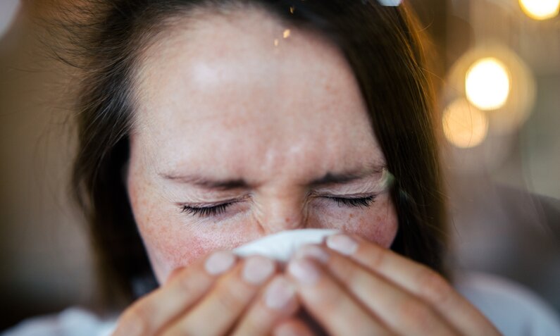 Frau niest in Taschentuch | ©  Getty Images/ Guido Mieth