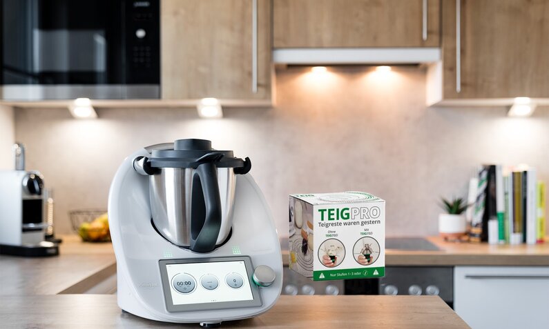 Thermomix tm6 auf Küchenanrichte daneben die Verpackung der TeigPro. | © Vorwerk / Wundermix