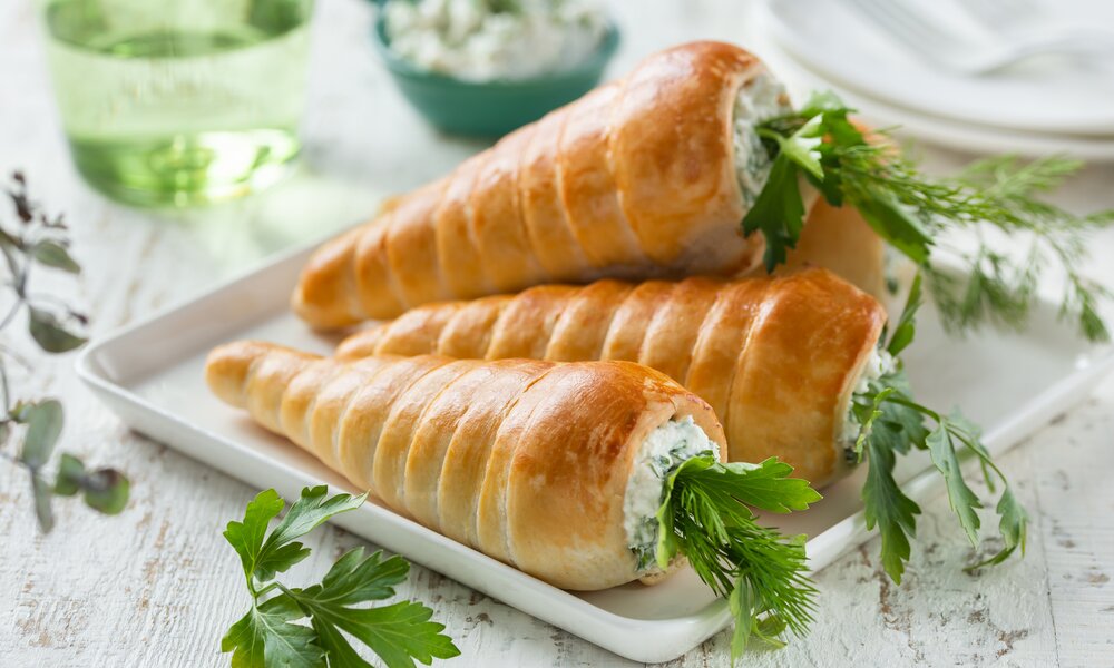 Hefebrötchen in Form von Möhren befüllt mit Frischkäsefüllung, auf einer Servierplatte liegend, angerichtet. | © Getty Images / Anna_Shepulova