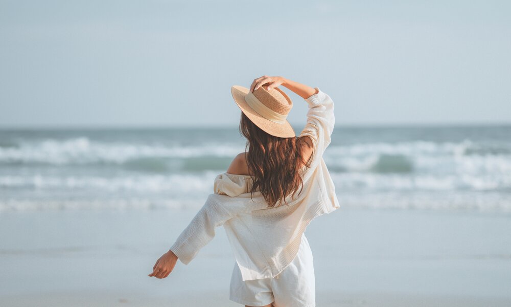 Frau steht am Strand und blickt aufs Meer | © Getty Images/oatawa