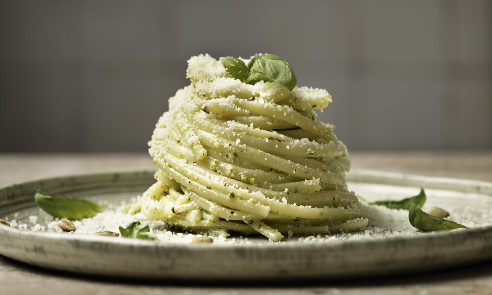 Spaghetti mit Basilikum und Parmesan bestreut, aufgedreht auf einem weißen Teller. | © Getty Images / 	Monica Bertolazzi