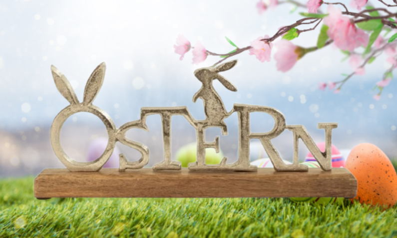 Aufsteller mit dem Schriftzug Ostern vor österlichem Hintergrund | © Amazon/Getty/loops7 
