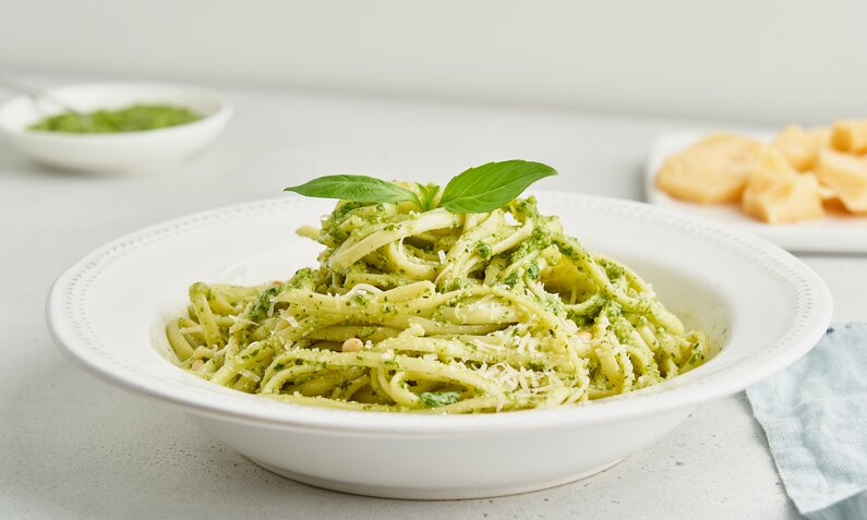Grüne Pasta mit Basilikum auf weißem Teller angerichtet. | © Getty Images / Natalia Gdovskaia