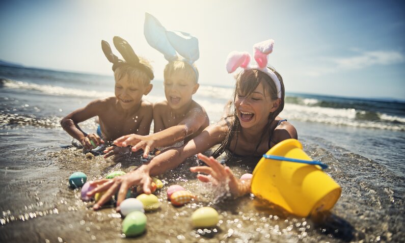 Kinder spielen am Strand mit Ostereiern  | ©  Getty Images/ Imgorthand