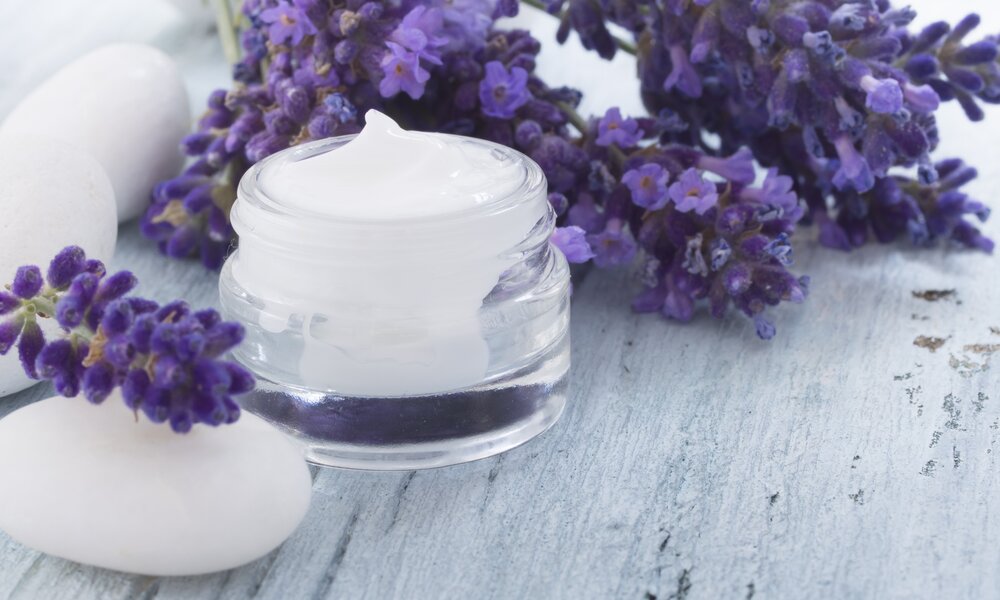 Weiße Creme in Tiegel, geöffnet, daneben frische Lavendel-Zweige. | © Getty Images / 	vesmil