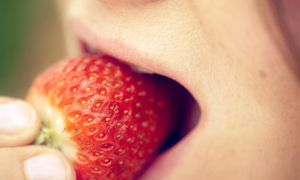 Frau beißt in Erdbeere, Closeup | ©  Getty Images/ Guido Mieth