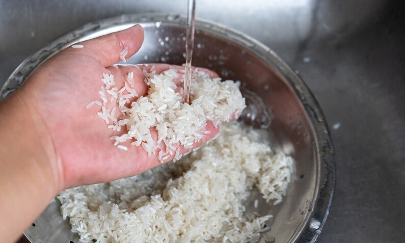 Hand wäscht weißen Reis unter fließendem Wasser in einem Sieb, Nahaufnahme. | ©  Getty Images/ carlosrojas20