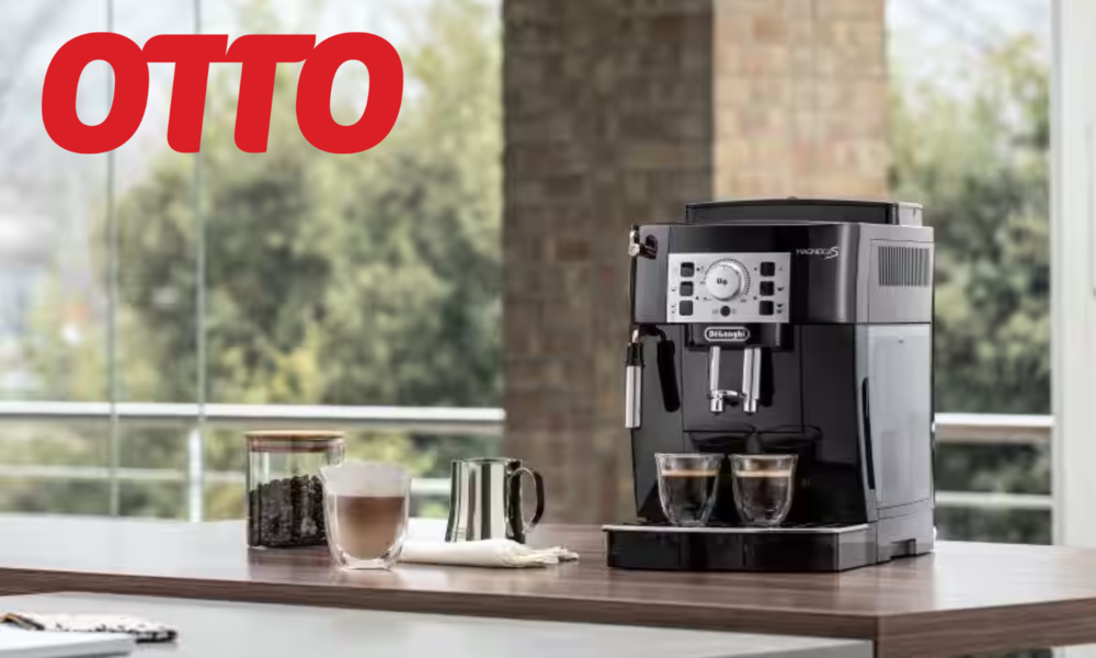 De'Longhi Magnifica S Kaffeevollautomat, daneben eine Tasse Cappuccino und aufgeschäumte Milch | © De'Longhi/Otto
