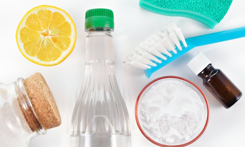 Ökologische Reinigungsmittel übersichtlich: Zitronenhälfte, Essigflasche, Natron, blaue Bürste. | ©  Adobe Stock/ geografika