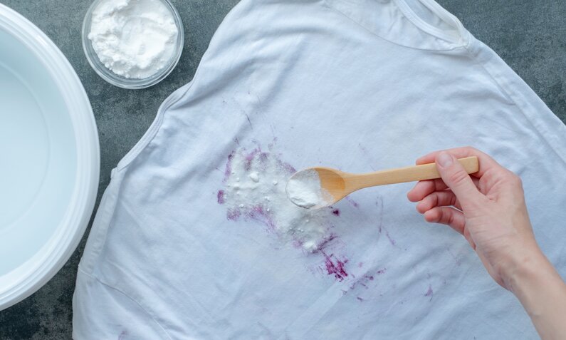 Fleckentfernung daheim: Backpulver auf einem beklecksten weißen T-Shirt. | ©  Getty Images/ Halyna Romaniv
