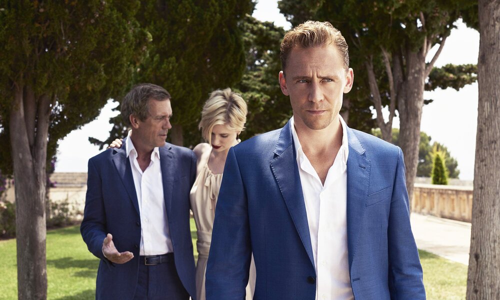 Tom Hiddleston, Hugh Laurie, Elizabeth Debicki spazieren unter Pinien in einer Szene aus der Serie "The Night Manager" | © Imago Images/Cinema Publishers Collection