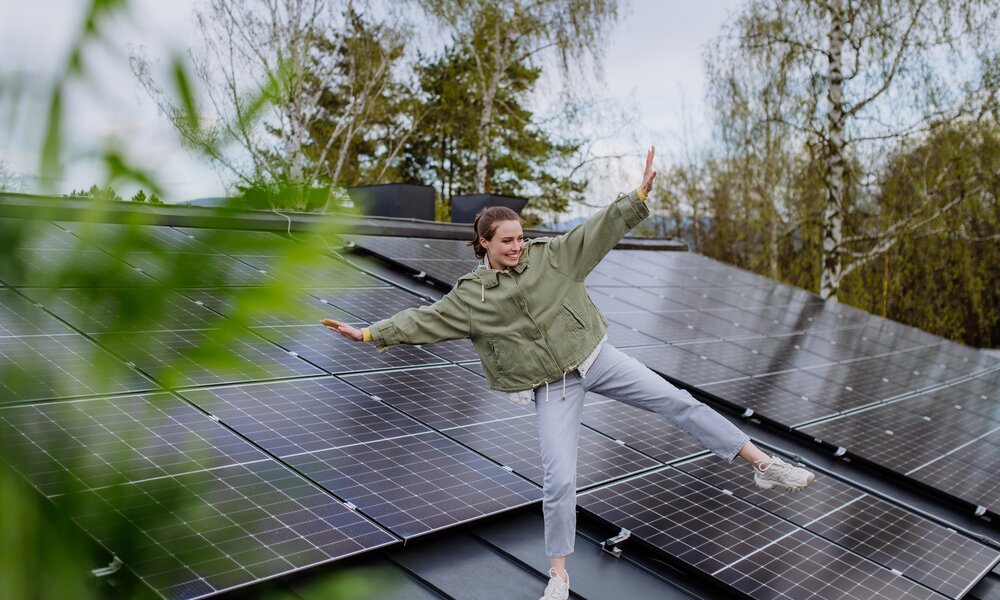 Frau läuft über ein Dach, auf dem Solarmodule installiert sein | © Getty Images/Halfpoint Images